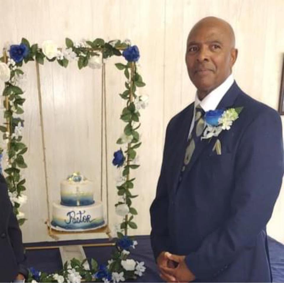 Rev. Perry Burden in a navy suit with a blue-and-white floral boutonniere